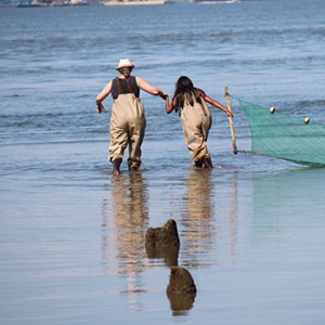 Two people in waders walking in the Hudson River