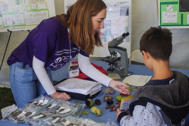 A volunteer in the Biology and Paleo Environment tent shows a future scientist samples of seeds and leaves from different kinds of plants found in bog environments. Photo: Phebe Pierson