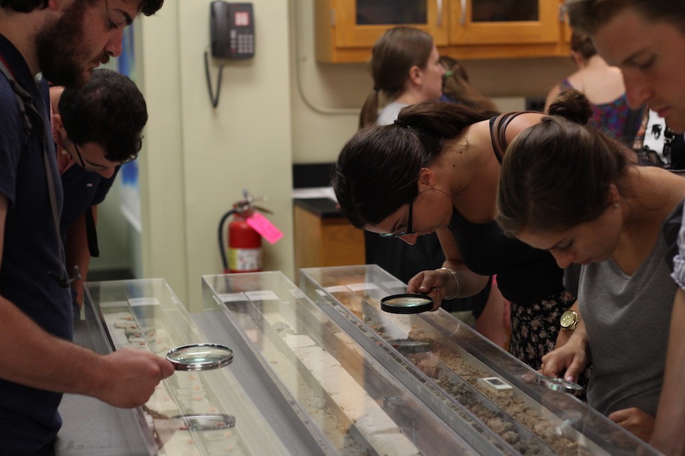 Attendees look at sediment cores under magnifying glasses