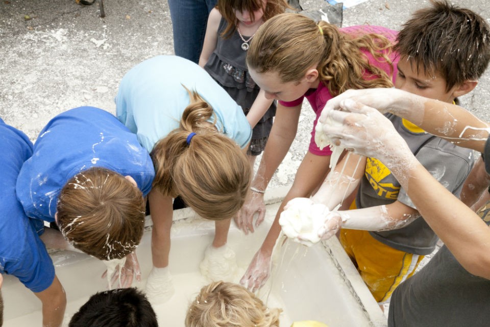 Kids feel the goopy cornstarch and water mix with their hands 