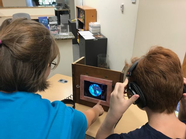 Kids listen to a simulation of Earth’s movements. Photo: Sarah Fecht kids listening with headphones