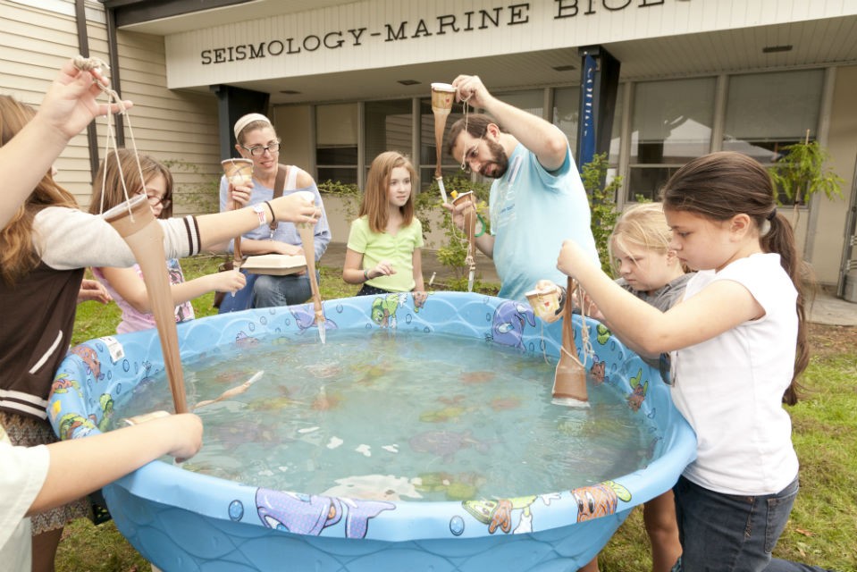 A plankton net of nylon stockings, string and a paper cup is used to fish for plankton. The catch is later analyzed under microscopes. Photo by Wade Martzall. group of children fishing for plankton out of a plastic pool