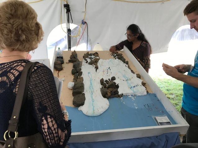 A goo made out of glue and Borax simulates the flow of glaciers. Toothpicks, originally placed in a straight line, illustrate how ice flows faster in the center due to lack of friction. Photo: Sarah Fecht goo flowing around rocks on a board
