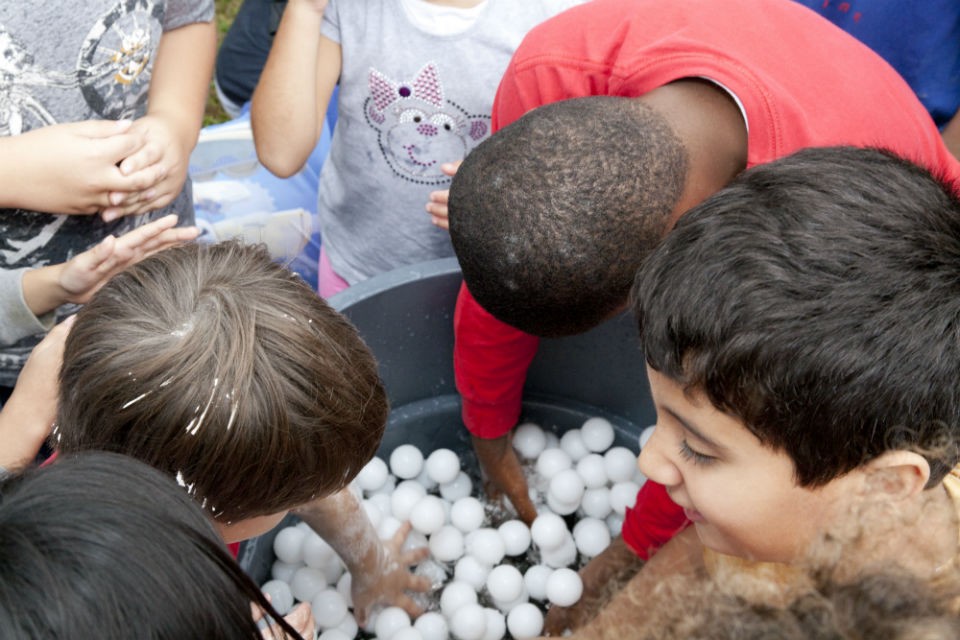 Ping pong and Wiffle balls stand in for lapilli and volcanic bombs in other eruption demonstrations. Here, visitors restock the next “trash can” eruption. Photo by Wade Martzall. attendees put ping pong balls into a trash can