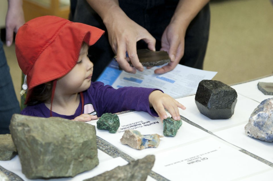Examples of the three types of rock found on earth—igneous, metamorphic and sedimentary—are on display for visitors to see and touch. Photo by Wade Martzall. Child touches different types of rocks in the rock touching room