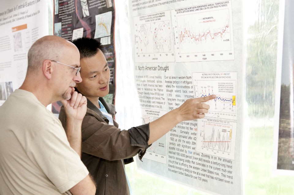 Scientist showing explaining research poster to attendee