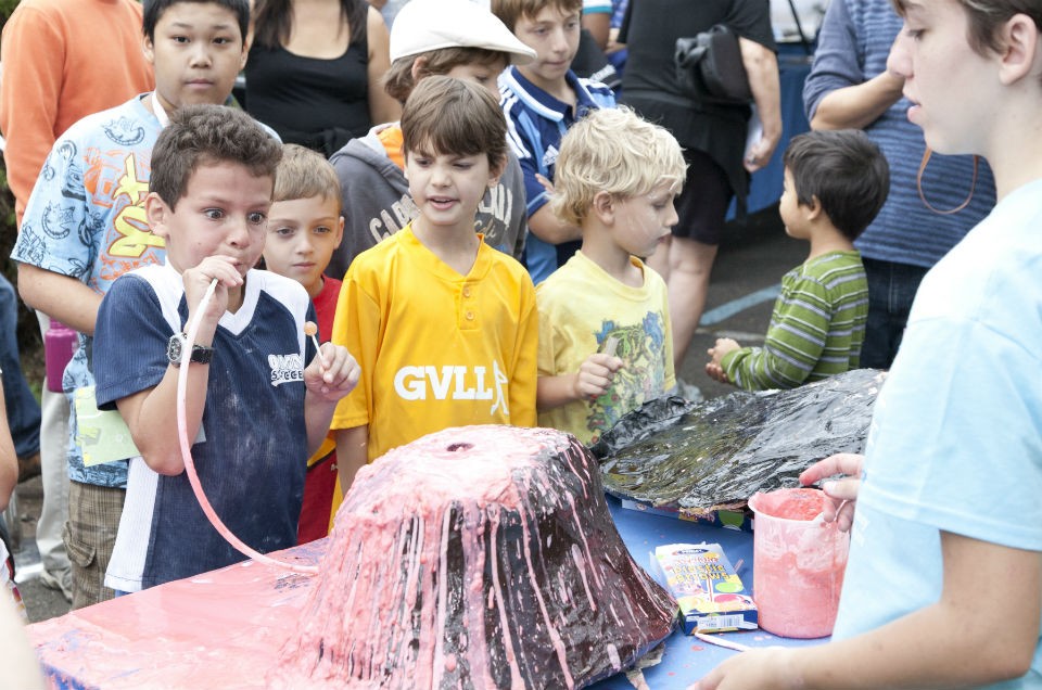 In a simulation of Strombolian eruptions, visitors increase gas pressure inside a volcano by blowing into a tube and forcing magma out of the cone. Photo by Wade Martzall child blows into tube to make volcano erupt