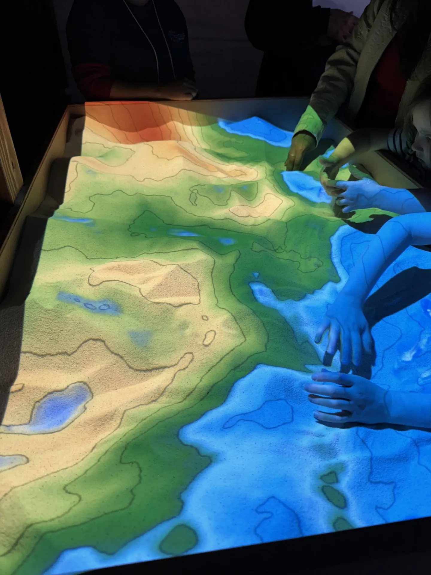 An augmented reality sandbox, where participants can help "map" the seafloor. Different colors represent different underwater depths.
