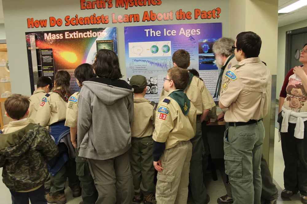 Boy scouts look at posters about mass extinctions and the ice ages