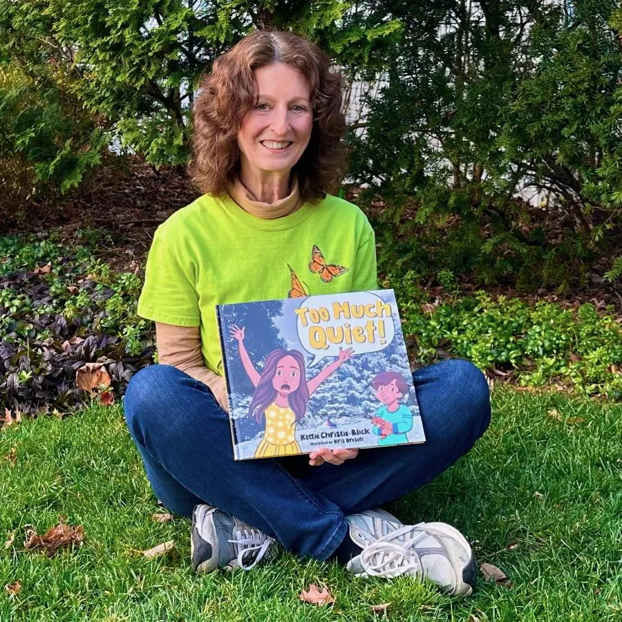 Author Kottie Christie-Blick holding a copy of her book Too Much Quiet!